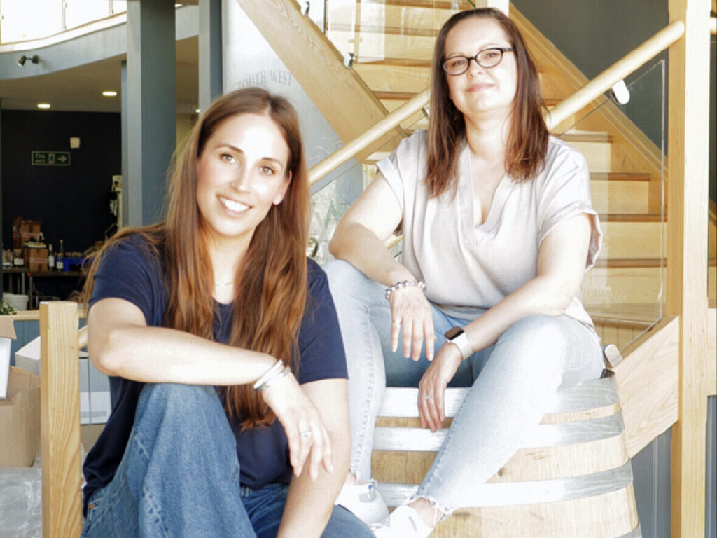An image of the two founders of 52North Drinks Gemma and Donna sitting on rum barrels.